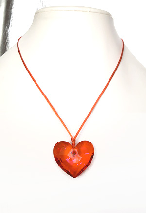 Collier coeur orange Pamplemousse. Ce collier est composé d'un grand coeur Swarovski orange à reflets roses à facettes étincelantes de 36mm, d'un cordon soyeux orange et d'un fermoir cuivré. La longueur de ce collier hors pendentif coeur est de 45 cm. Bijou haute fantaisie de marque Azebra Mint. Bijou luxe de fabrication française.