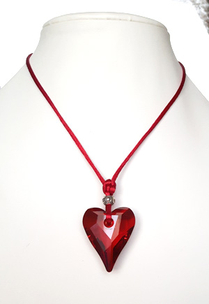 Collier coeur rouge sur soie. Ce collier est composé d'un grand coeur Swarovski rouge étincelant de 37mm, d'un cordon soyeux rouge et d'un fermoir argenté et chaînette. La longueur de ce collier hors pendentif coeur est de 42 cm, ajustable jusqu'à 45cm. Bijou haute fantaisie de marque Azebra Mint. Bijou luxe de fabrication française.